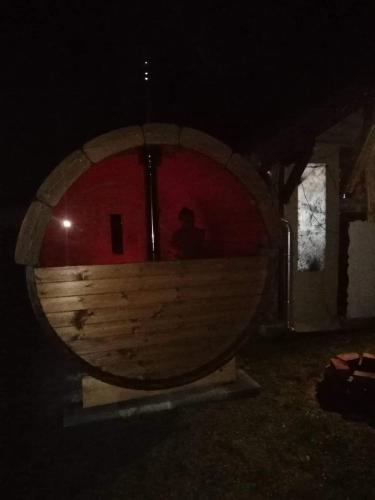 a man standing in front of a wooden barrel at night at Jakuzzis,Szaunás,Kerkavendégház-Őrség-Csesztreg-Kerkaujfalu in Csesztreg