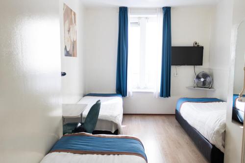 a small room with two beds and a window at Hotel Doria in Amsterdam