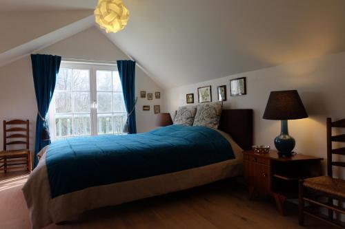 um quarto com uma cama azul e uma janela em B&B Asbeek em Asse