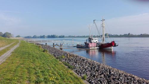 un barco está atracado en un muelle en el agua en Ferienwohnung Elbe Diek en Stelle