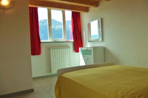 sypialnia z łóżkiem i 2 oknami z czerwonymi zasłonami w obiekcie Casa le Palme w mieście Pino Lago Maggiore