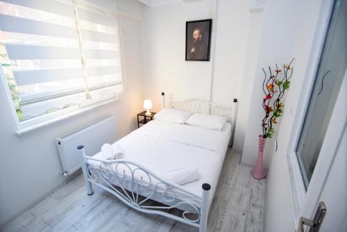 a white bedroom with a bed and a window at Arney Suites in Eskisehir