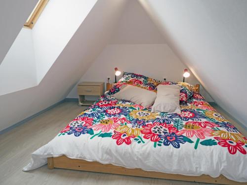 a bed with a colorful blanket on it in a attic at Le 128, duplex alsacien 10 personnes, piscine in Horbourg