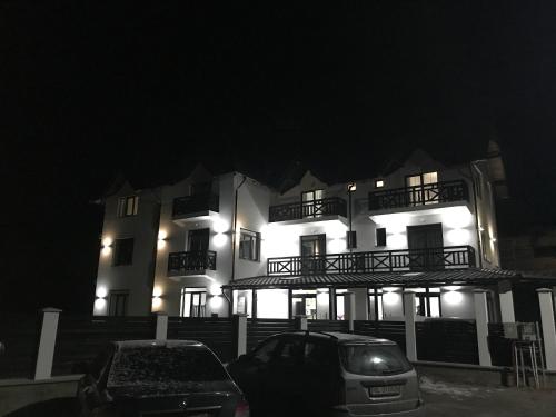 a building with a car parked in front of it at night at Pensiunea Edelweiss in Voineasa