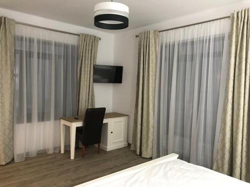a bedroom with a desk and a bed and curtains at Pensiunea Edelweiss in Voineasa