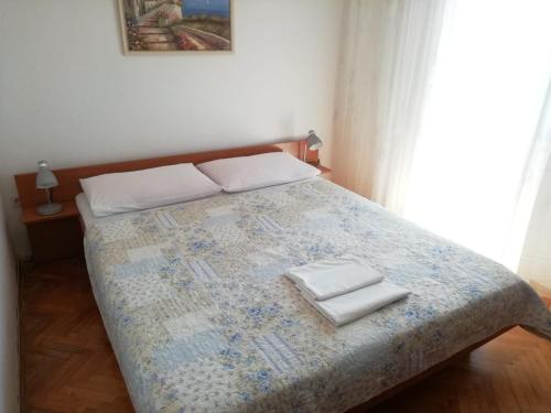 a bedroom with a bed with two pillows on it at Apartmani Kelava in Podgora
