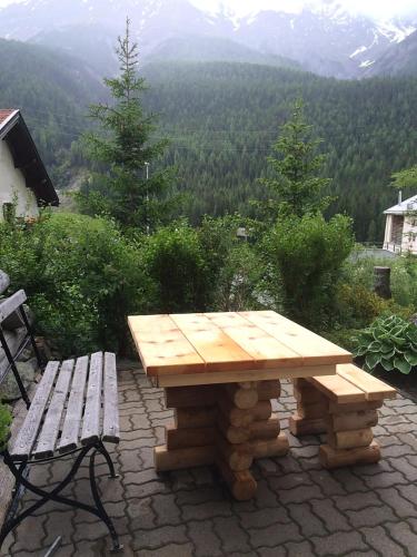a wooden picnic table and a bench on a patio at Chesa Sper l'Ovel Brail in Zernez