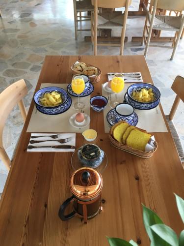 einem Holztisch mit Teller mit Lebensmitteln und Gläsern Orangensaft in der Unterkunft El Lugar Boutique Hotel in Pereira