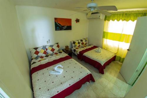 1 dormitorio con 2 camas y ventilador de techo en Posada Caribbean Refuge, en San Andrés