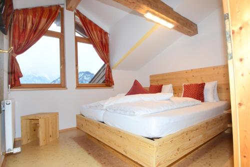 a bedroom with a wooden bed in a room with windows at Haus Salvenmoser in Walchsee