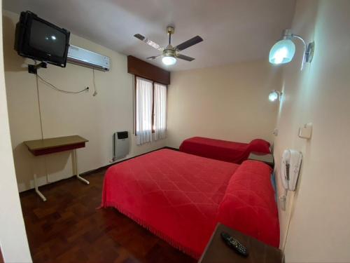 a bedroom with a red bed and a flat screen tv at Hotel Villa Inés Mendoza in Mendoza