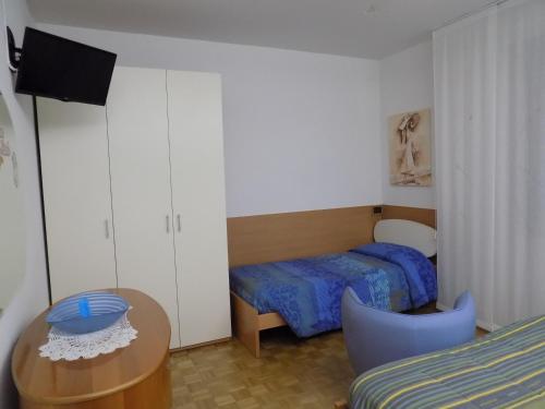 Dormitorio pequeño con cama, mesa y TV en Aparthotel Feeling at Home, en Castenaso