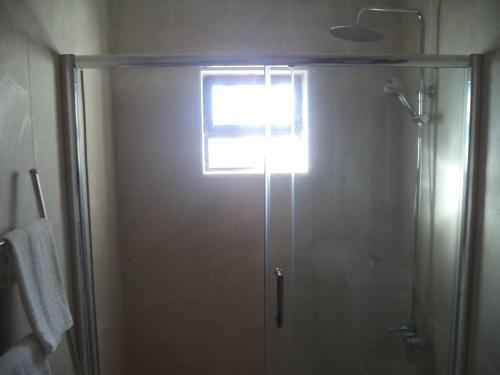 a shower with a glass door in a bathroom at Quartos Maria Clara in Sagres