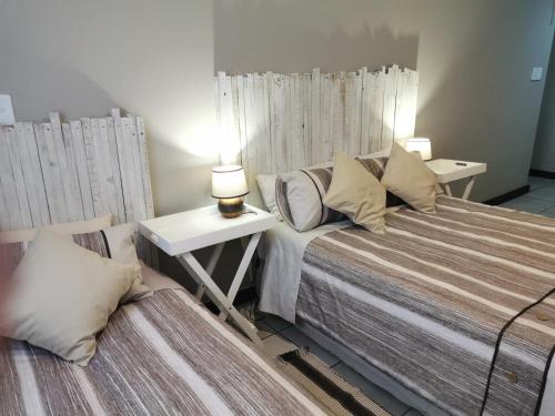 a bedroom with two beds and two tables and lamps at Kom Kuier Self-Cater in Vredenburg