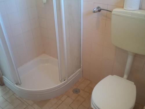 a bathroom with a white toilet and a shower at Quartos Maria Clara in Sagres