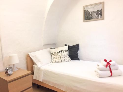 a bedroom with a white bed with a bow on it at Trulli Garden in Alberobello
