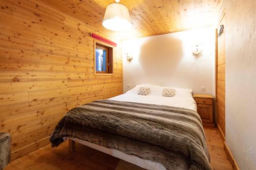 ein Schlafzimmer mit einem Bett in einer Holzwand in der Unterkunft Appartement Marcella in Montgenèvre