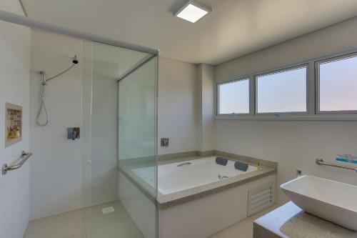uma casa de banho com uma banheira, um chuveiro e um lavatório. em Pousada Ilha Faceira em Florianópolis