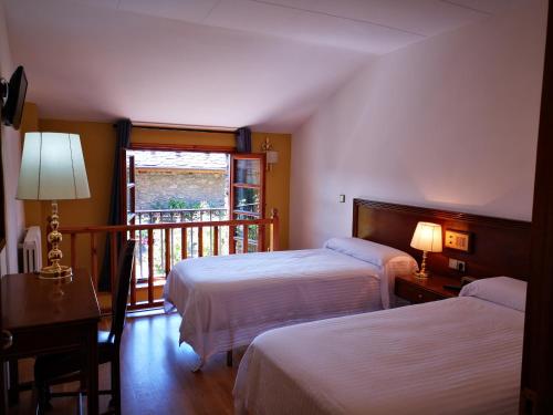 a hotel room with two beds and a balcony at Hotel Santa Bàrbara De La Vall D'ordino in Ordino