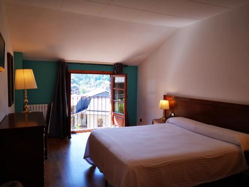 ein Schlafzimmer mit einem Bett und einem großen Fenster in der Unterkunft Hotel Santa Bàrbara De La Vall D'ordino in Ordino