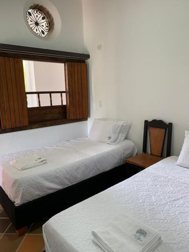 two beds in a room with a clock on the wall at Hotel la hacienda del pienta in Charalá