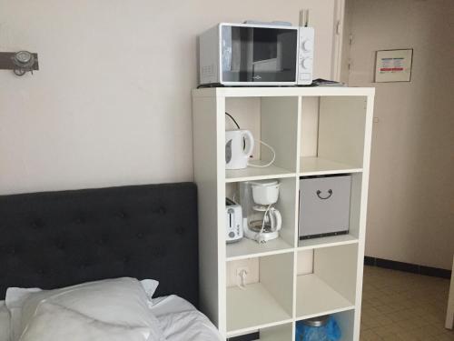 - une étagère blanche avec un four micro-ondes et un lit dans l'établissement Studio 2 pers en vieille ville parking gratuit - by La Source d'OrFée, à Boulogne-sur-Mer