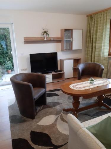 ein Wohnzimmer mit einem Tisch, Stühlen und einem TV in der Unterkunft Ferienwohnung Viktoria in Lenzkirch