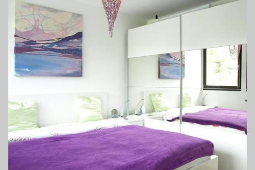 2 camas con sábanas moradas en una habitación con ventanas en Ferienhaus DANA, en Meschede
