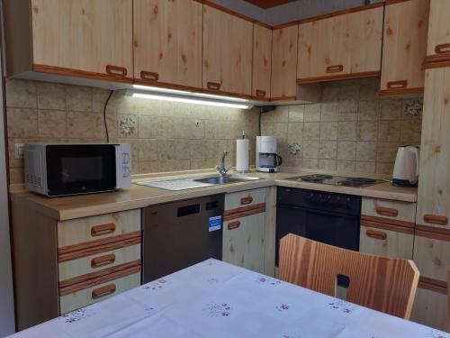 eine Küche mit Holzschränken, einer Spüle und einer Mikrowelle in der Unterkunft Ferienwohnung Viktoria in Lenzkirch