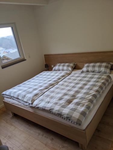 una camera da letto con un letto con un piumone a quadri e una finestra di Ferienhaus Schieferterrasse - Waldsee Rieden - a Rieden