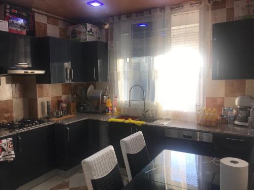 a kitchen with a sink and a window with chairs at Super appartement de luxe T4 a la ville de Bejaia in Bejaïa