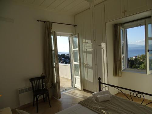 a bedroom with a bed and two windows and a balcony at Villa ADA in Hydra