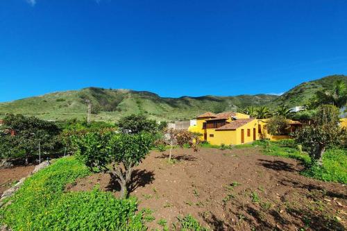 a yellow house on a hill with mountains in the background at Casa emblemática in Tegueste