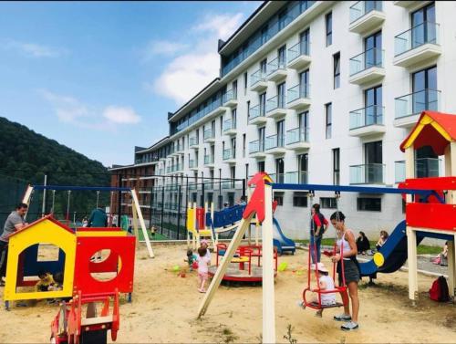 a group of children playing in a playground in front of a building at ORBI PALACE DELUX Bakuriani room 470 in Bakuriani