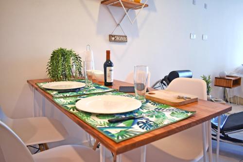 a table with plates and a bottle of wine on it at Luminosos y modernos departamentos en Rosario in Rosario