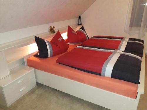 Una cama con almohadas rojas y negras. en Ferienwohnung direkt am See en Bad Saarow
