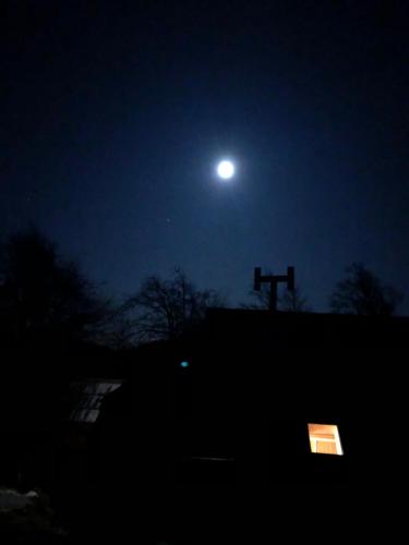 a moon over a building with a cross in the night at Mountain Lodge Suška Koča in Stahovica