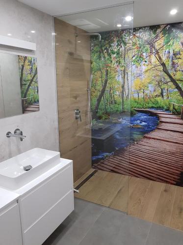 a bathroom with a shower with a painting of a river at Forest House - Domy Mazur in Regiel