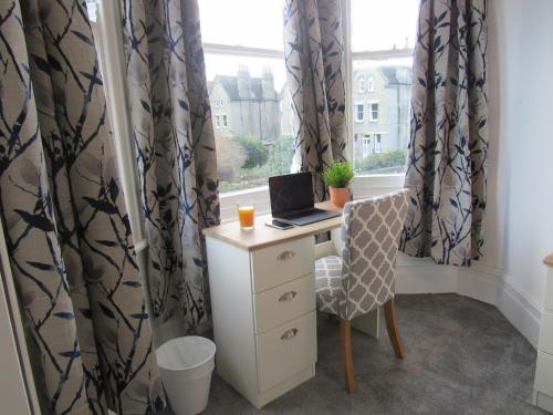 een bureau met een laptop voor een raam bij The Tas Suites - Tas Accommodations in Cambridge