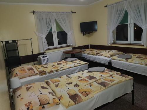 a group of four beds in a room with windows at Pokoje Relaks 2 in Gdynia