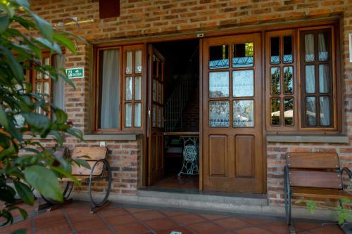 una puerta delantera de un edificio de ladrillo con dos bancos en Hostal Canela en Termas del Daymán