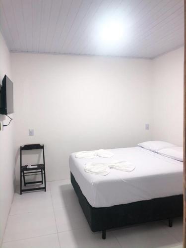 a white room with a bed and a television at Suítes Da Vila 152 in Praia do Forte