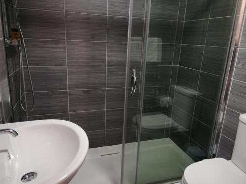W łazience znajduje się prysznic, umywalka i toaleta. w obiekcie Gillygate Guest House w mieście York