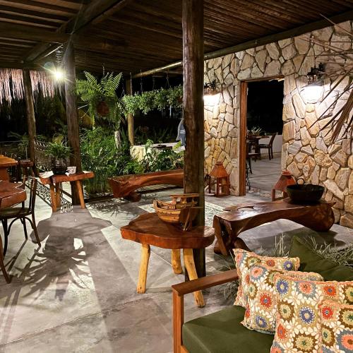 a patio with tables and chairs and a stone wall at Ocacocar - Milagres in São Miguel dos Milagres