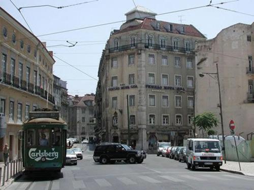 a city street with cars and a green trolley at Pensao Nova Goa in Lisbon
