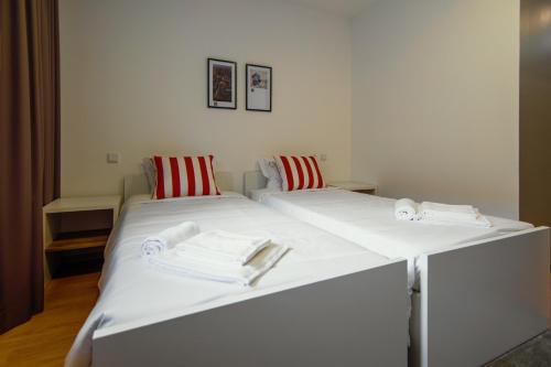two beds in a room with white sheets and red pillows at HI Braga - Pousada de Juventude in Braga