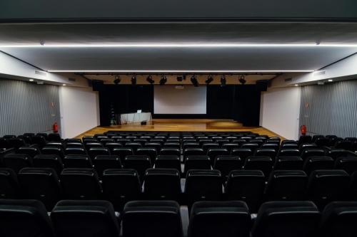 an empty auditorium with black chairs and a stage at HI Braga - Pousada de Juventude in Braga