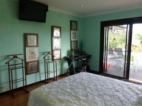 a bedroom with a bed and a television on the wall at Le Médipole in Noumea