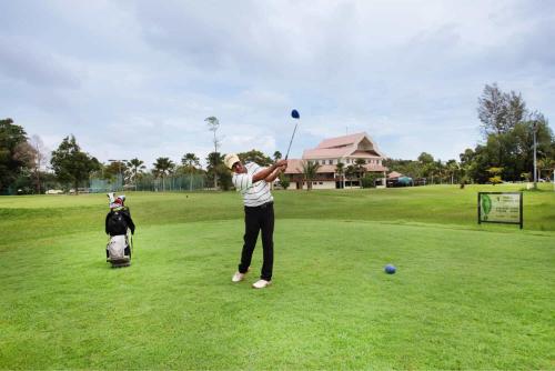 une femme qui fait basculer un club de golf sur un parcours de golf dans l'établissement Kuala Terengganu Golf Resort by Ancasa Hotels & Resorts, à Kuala Terengganu