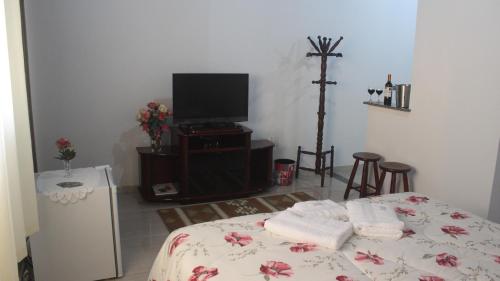 a room with a bed and a tv and a cross at Luxor Flat`s in Miguel Pereira